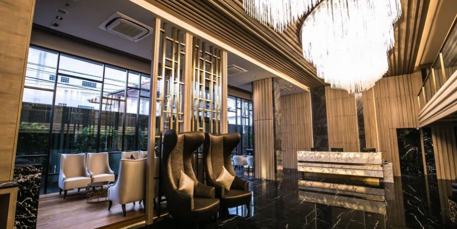 Interior view of Arte Hotel Bangkok lobby showcasing a grand chandelier and stylish chairs for guests.